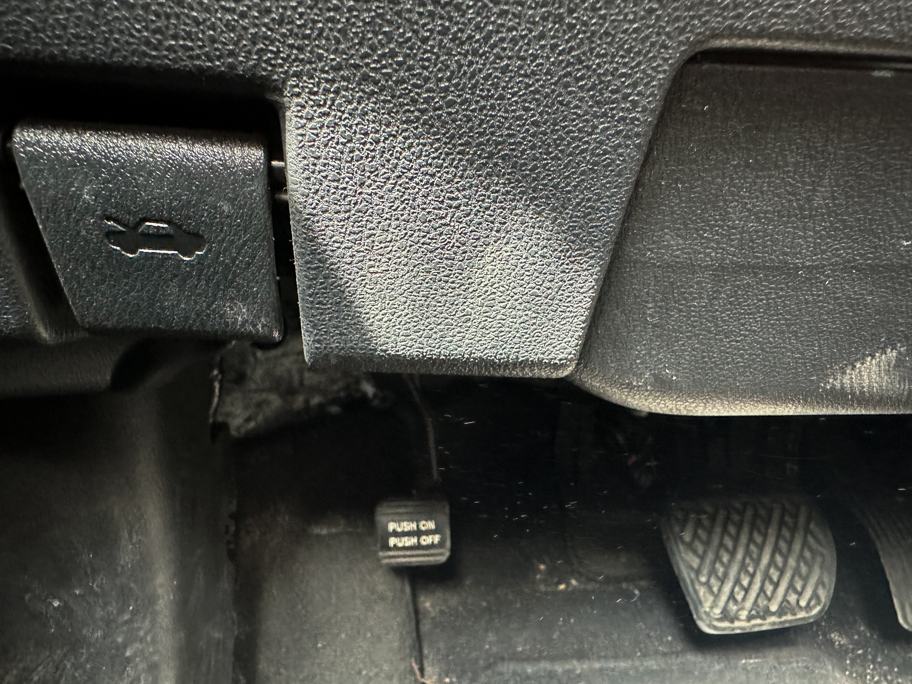A photo of the Nissan Leaf parking brake lever in its on position, located near the gas and brake pedals