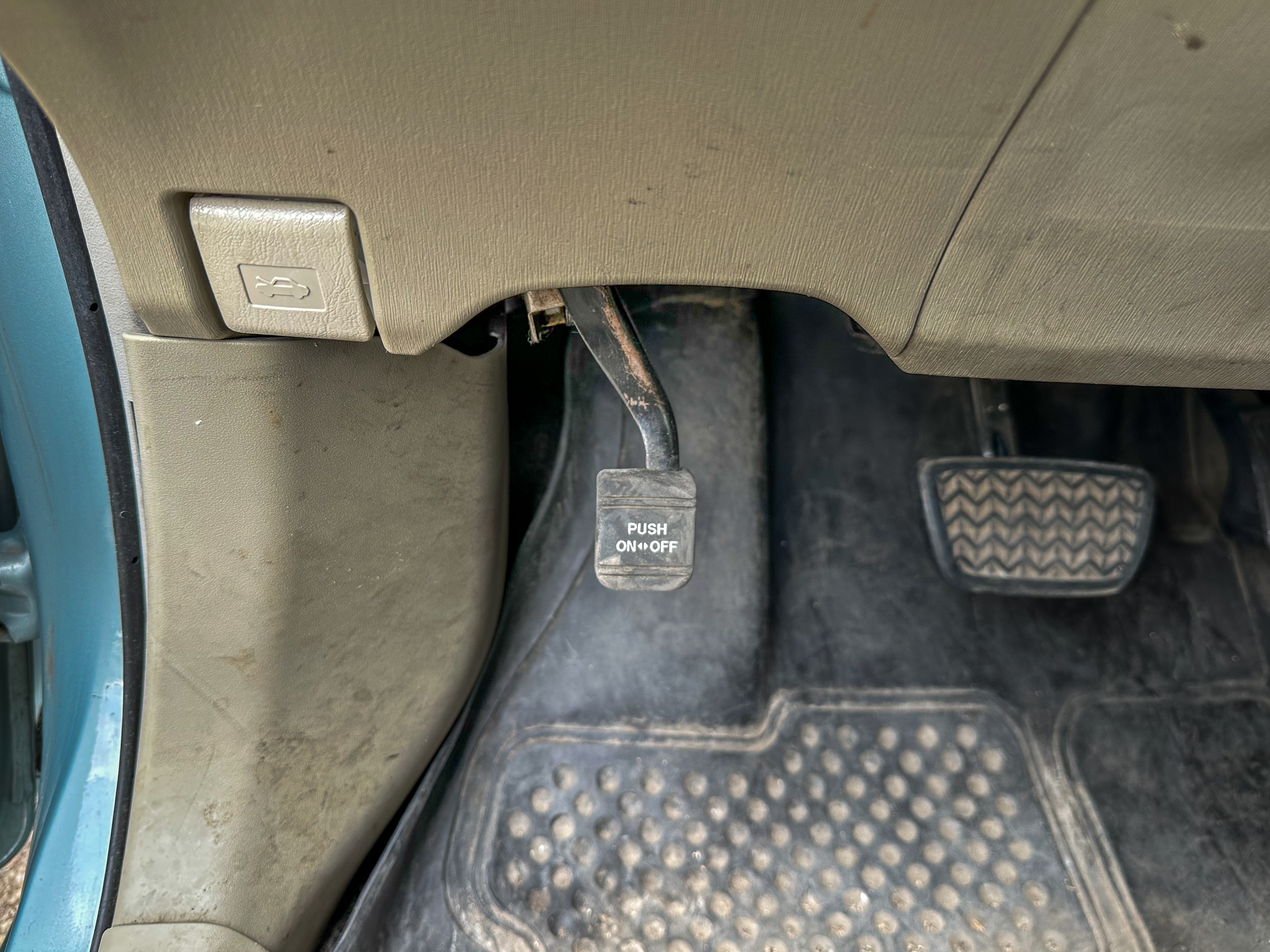 A photo of the Toyota Prius parking brake pedal in its off position, located near the gas and brake pedals